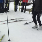 person w bent knees surrounded by people learning to ski